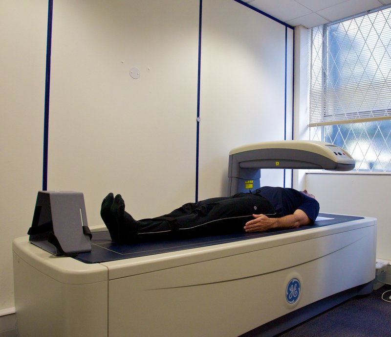 DEXA bone densitometry scanner with the scanning arm positioned over a patient lying on the table